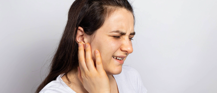 Child holding their ear in discomfort, showing symptoms of a possible ear infection.