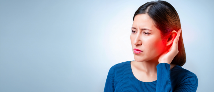 woman holding her ear in visible discomfort due to a ruptured eardrum.