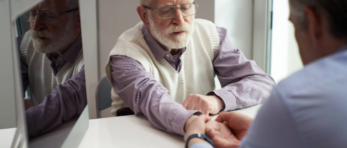 Doctor examining an elderly man's wrist for osteoarthritis symptoms