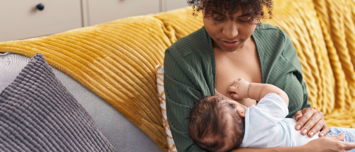 A mother breastfeeding her infant in a cozy, sunlit room, symbolizing the health benefits of breastfeeding for both mother and baby.