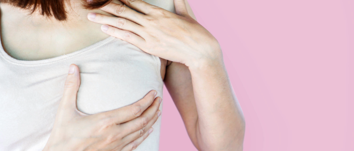 Woman performing a breast self-exam to check for early signs of breast cancer.