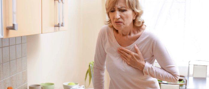 Middle-aged woman experiencing chest pain, a possible early sign of heart disease.