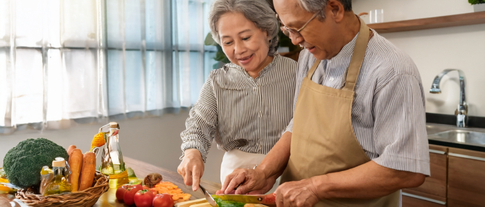 Senior couple preparing a brain-healthy meal rich in vegetables and olive oil.