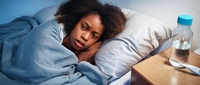 sick person recovering from norovirus symptoms with a water bottle and blanket.