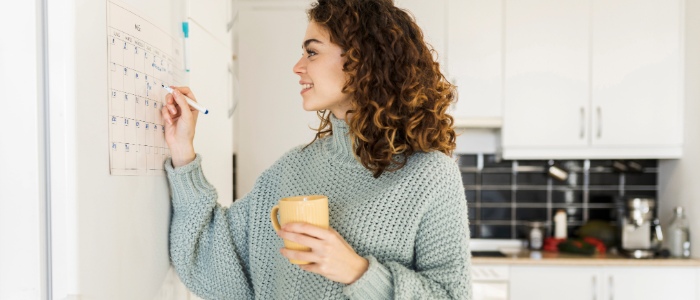 Woman tracking her menstrual cycle with a calendar while holding a coffee mug