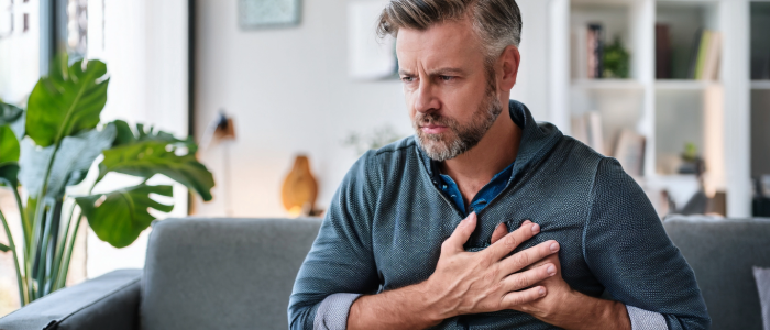 Adult holding chest with discomfort, possibly experiencing early signs of heart failure.